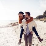 man carrying woman on a beach